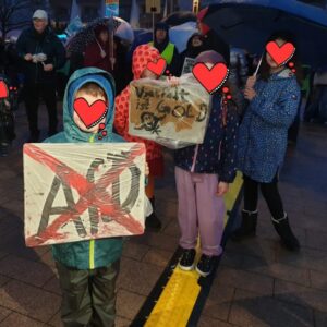 Kinder mit Demoschild.
Gesicht durch Herz unkenntlich.
